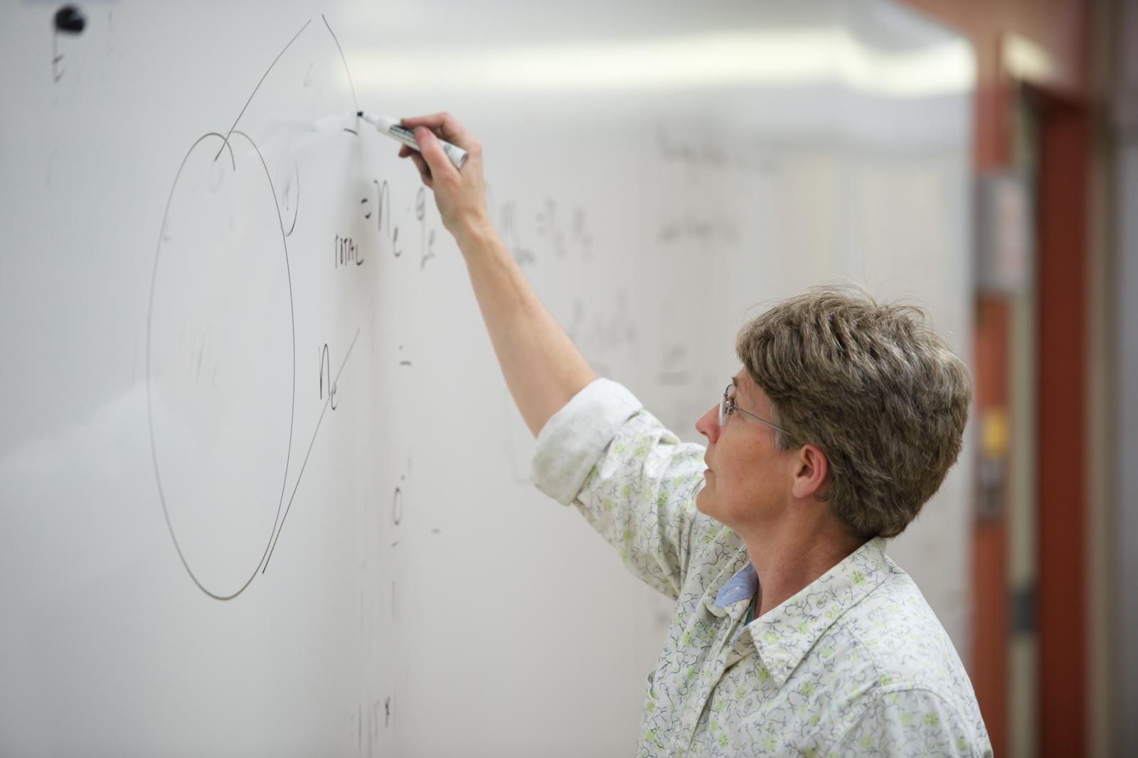 Instructor works out a problem on the whiteboard