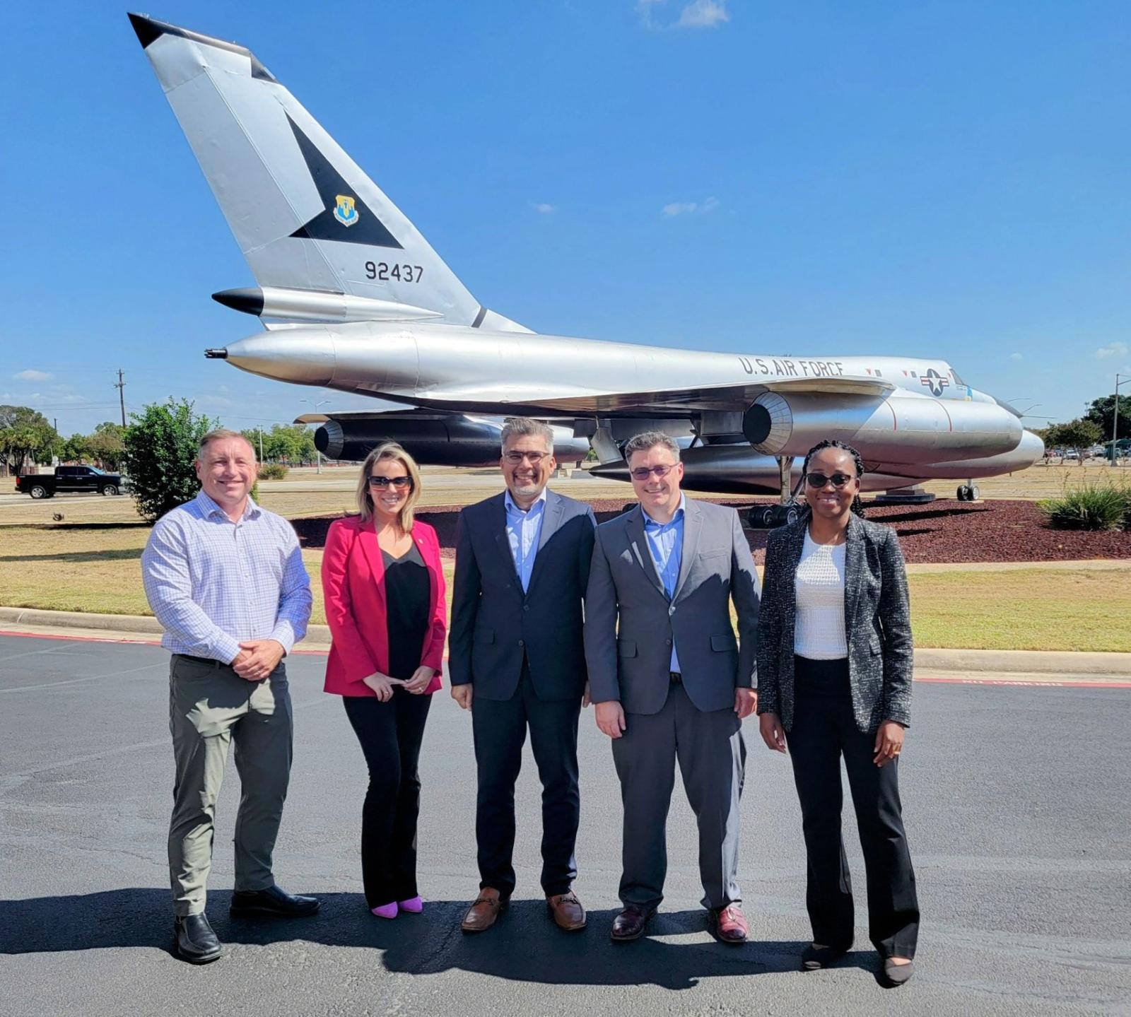 A group of people pose for a picture in front of a decommissioned Air Force fighter jet.